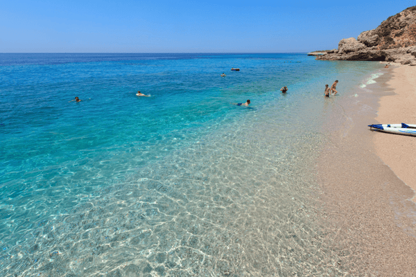 Moderna plaža Drymades s bijelim kamenčićima, tirkiznim morem i stylish beach barovima